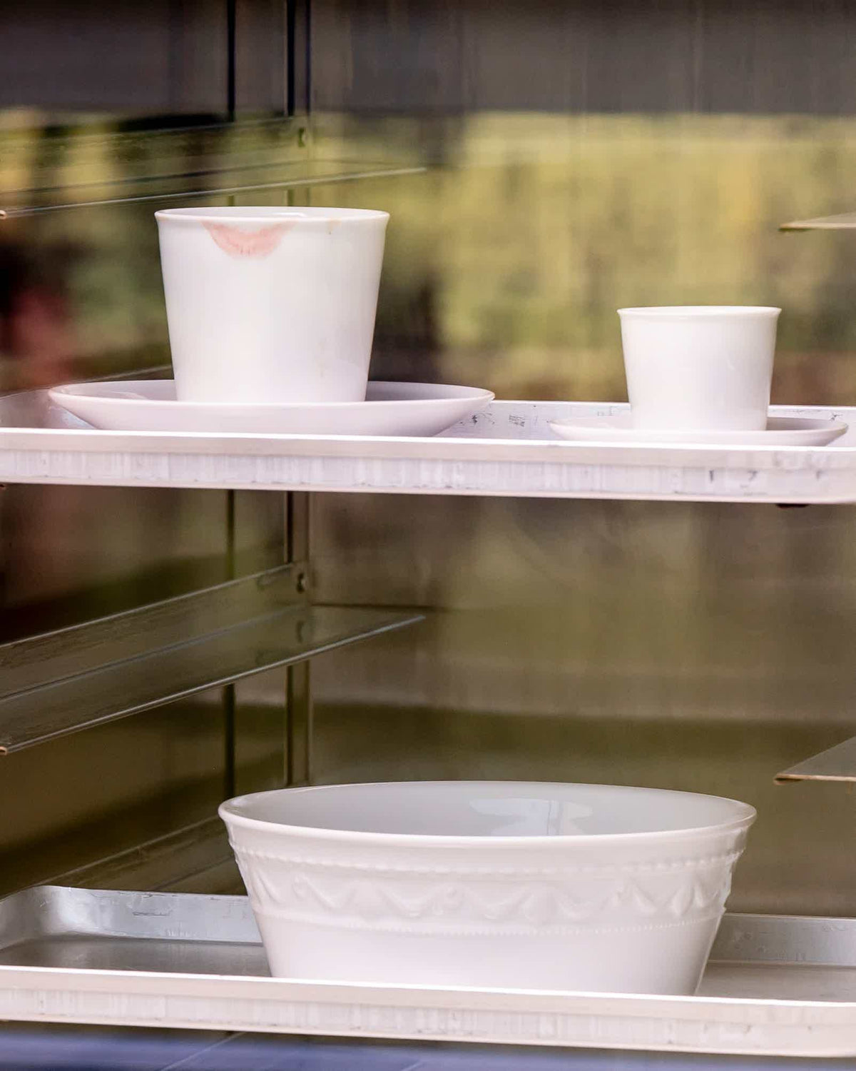 Weiße Keramikschalen und -tassen auf einem Regal.