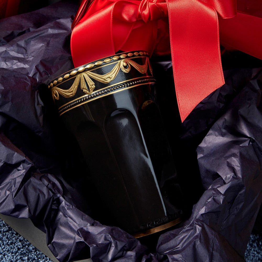 Eine dekorative schwarzer KPM Champagnerbecher in einer Geschenkverpackung mit roter Schleife.