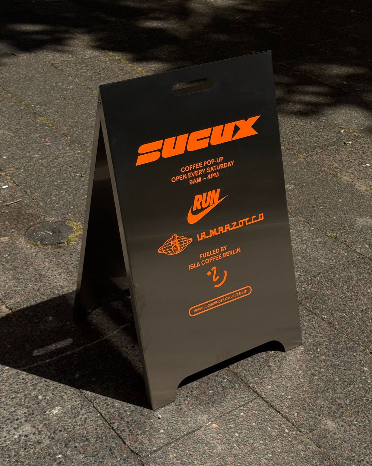 Schwarzes Schild mit der Aufschrift „SUCUX“ und Logos verschiedener Marken.