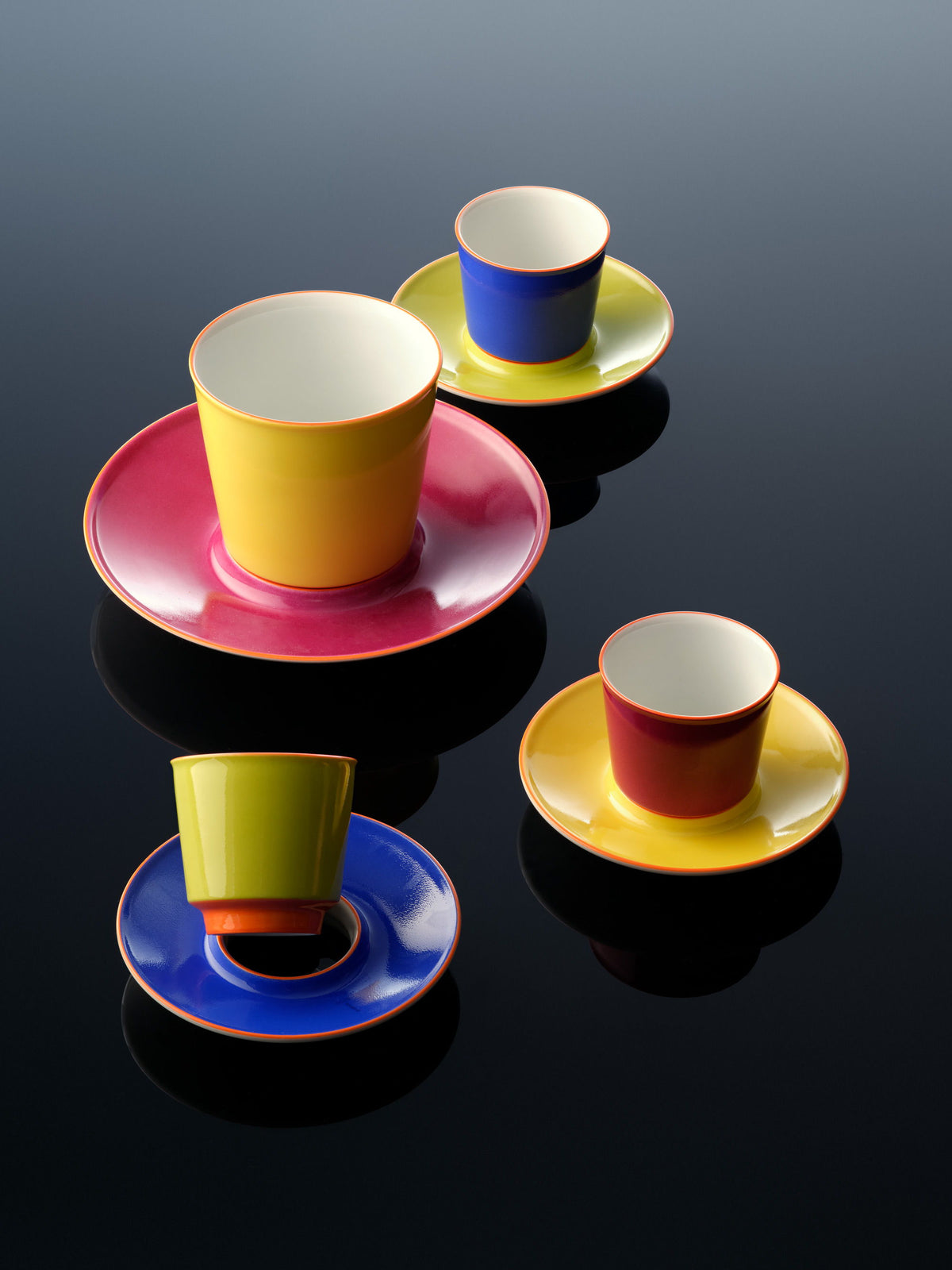 tazas de avión de colores, dispuestas sobre una superficie reflectante.