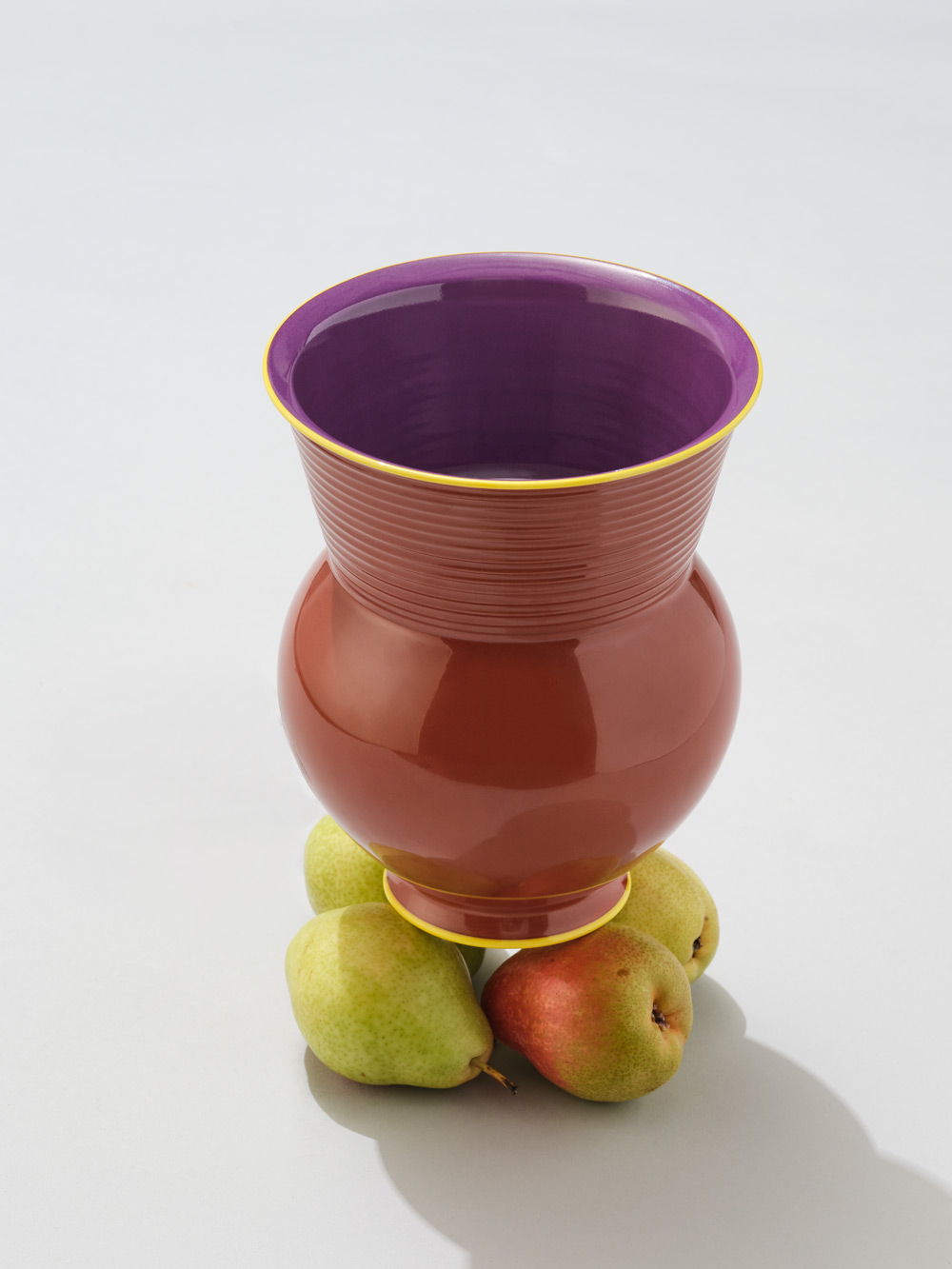 Un jarrón de KPM+ Gisbert Pöppler Halle sobre tres manzanas.