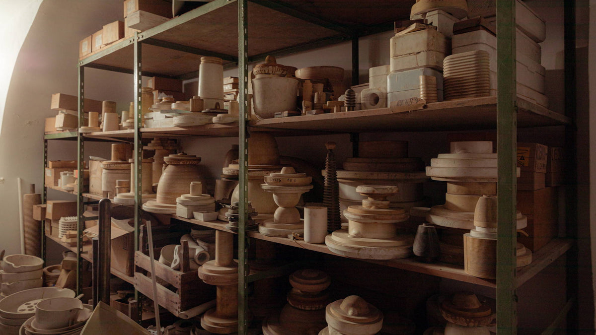 Shelves with various pottery and ceramic objects in a storage room.